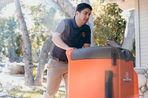 water damage restoration professional moving equipment into house