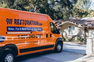 911 Restoration orange van parked in driveway of house