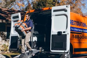 disaster restoration technician taking equipment out of truck